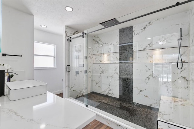 full bath with a textured ceiling, recessed lighting, wood finished floors, a sink, and a marble finish shower