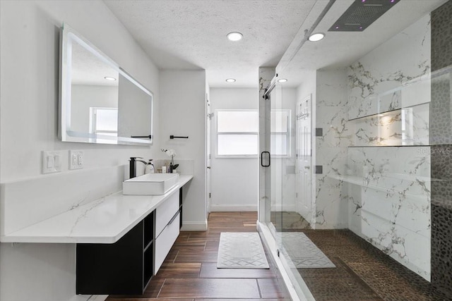 bathroom featuring a marble finish shower, wood tiled floor, a textured ceiling, vanity, and recessed lighting