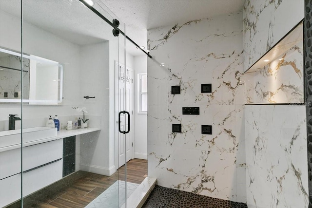 full bathroom featuring a textured ceiling, vanity, a marble finish shower, and wood finished floors