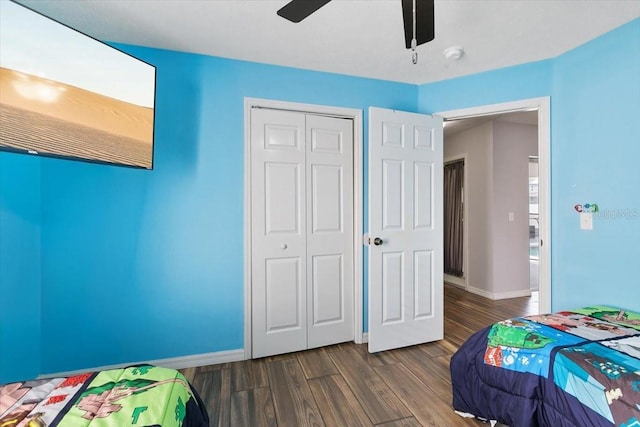 bedroom featuring dark wood-style floors, a ceiling fan, baseboards, and a closet