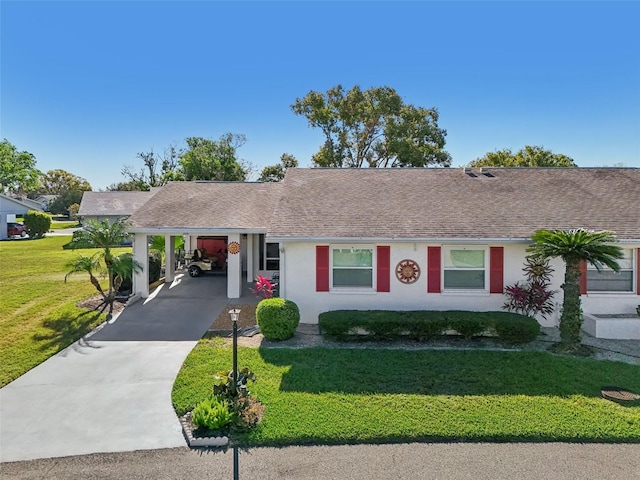 ranch-style home with a shingled roof, a front yard, driveway, and stucco siding