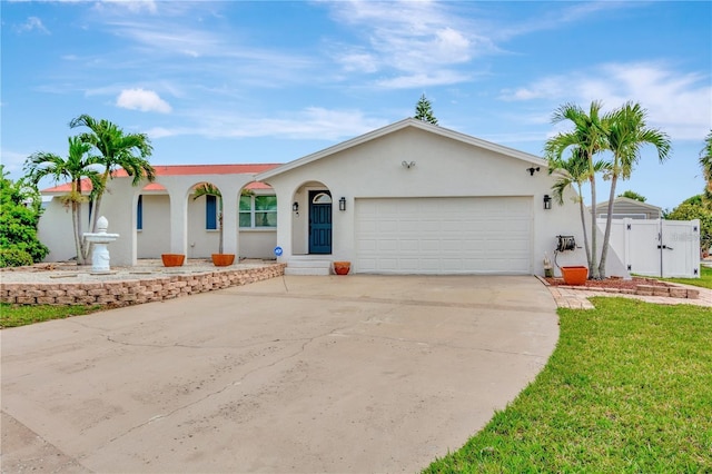 ranch-style home with concrete driveway, an attached garage, a gate, fence, and stucco siding