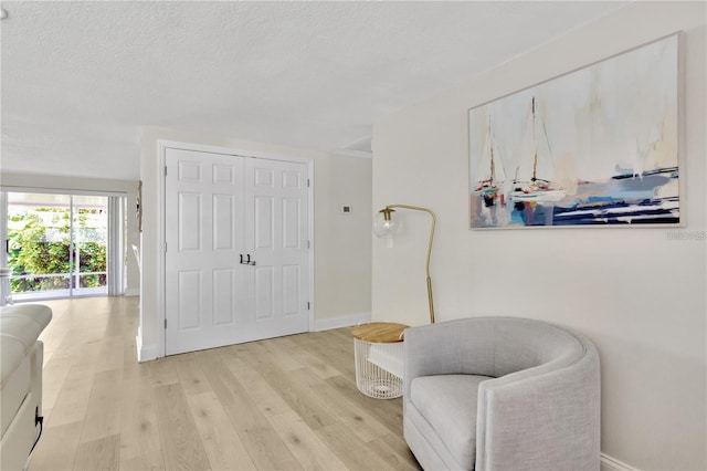 living area with light wood-style floors, baseboards, and a textured ceiling