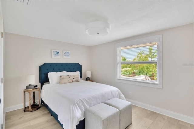 bedroom featuring light wood-style floors, visible vents, and baseboards