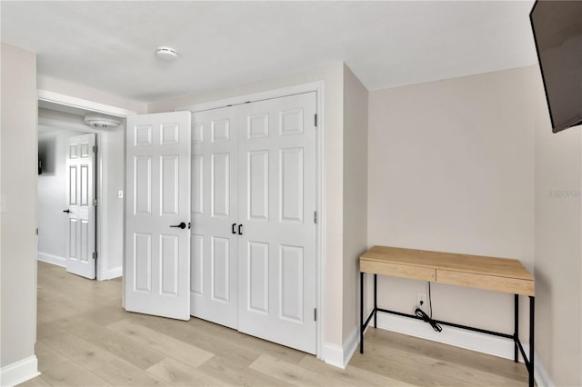 hall with light wood-style flooring and baseboards