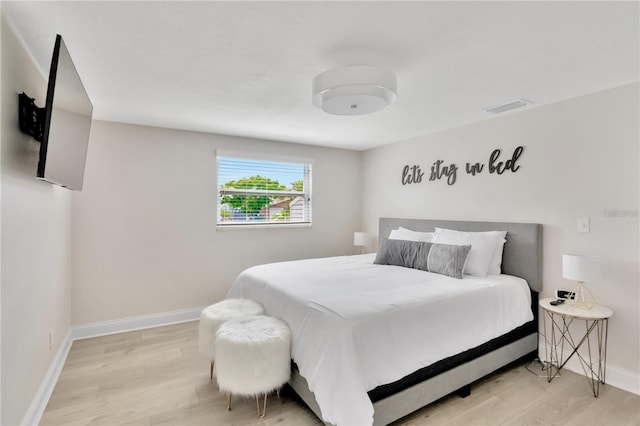 bedroom featuring light wood-style flooring, visible vents, and baseboards