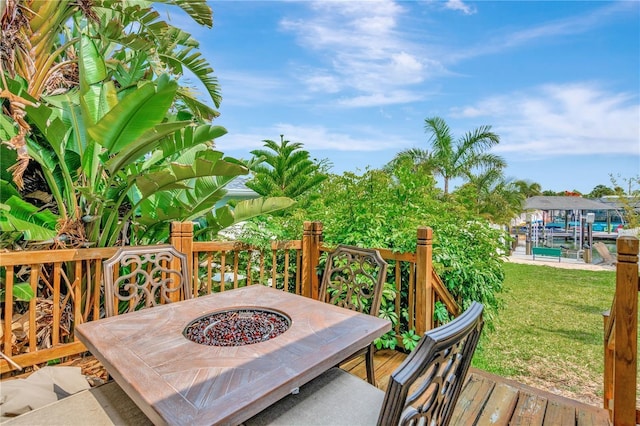 wooden deck with a yard, an outdoor fire pit, and a boat dock