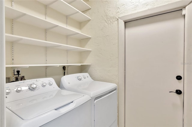 washroom featuring a textured wall, laundry area, and washer and dryer