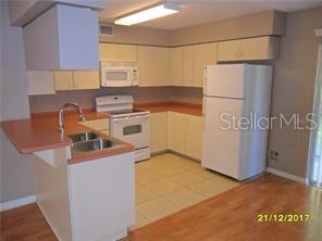 kitchen with visible vents, a sink, white appliances, a peninsula, and baseboards