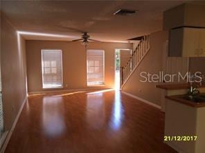 unfurnished living room featuring ceiling fan, wood finished floors, visible vents, baseboards, and stairs