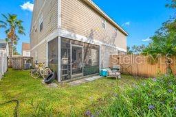 rear view of house with a sunroom, a fenced backyard, and a yard