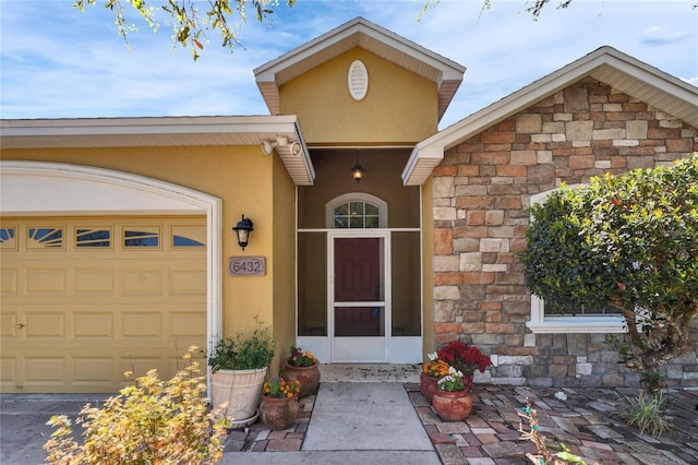 entrance to property featuring stone siding, an attached garage, and stucco siding