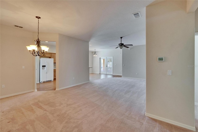 unfurnished living room with light colored carpet, visible vents, baseboards, and ceiling fan with notable chandelier