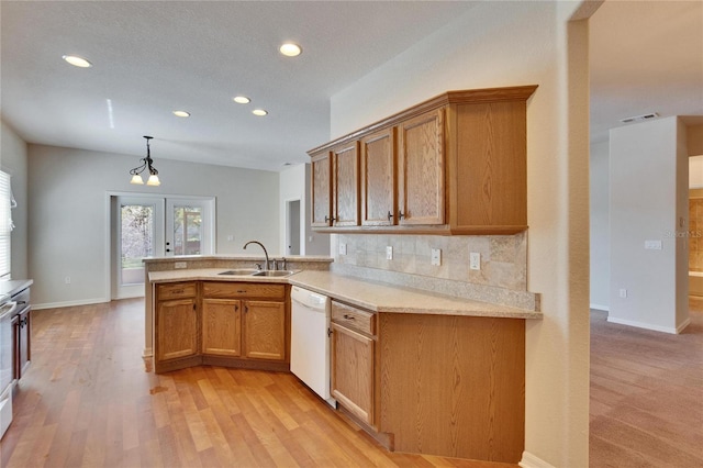 kitchen with visible vents, decorative backsplash, white dishwasher, light countertops, and a sink