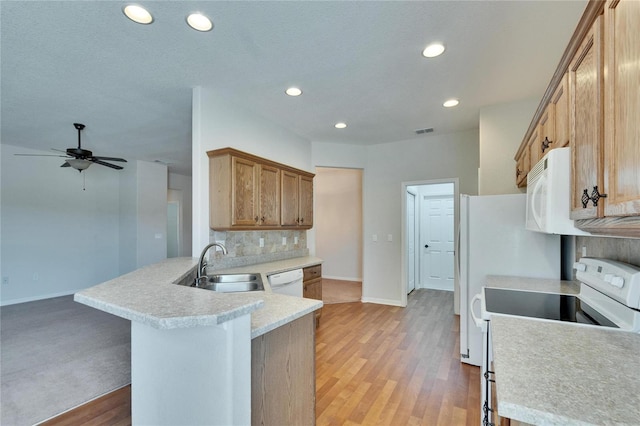 kitchen with light countertops, visible vents, backsplash, a sink, and white appliances