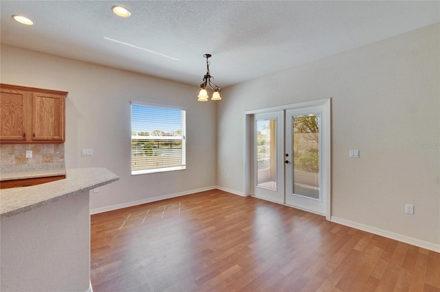 unfurnished dining area featuring french doors, recessed lighting, a textured ceiling, light wood-type flooring, and baseboards