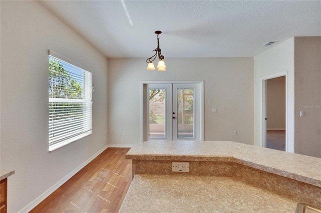 interior space with light wood finished floors, baseboards, visible vents, french doors, and a chandelier