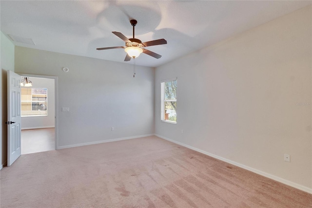 empty room with light colored carpet, ceiling fan, visible vents, and baseboards