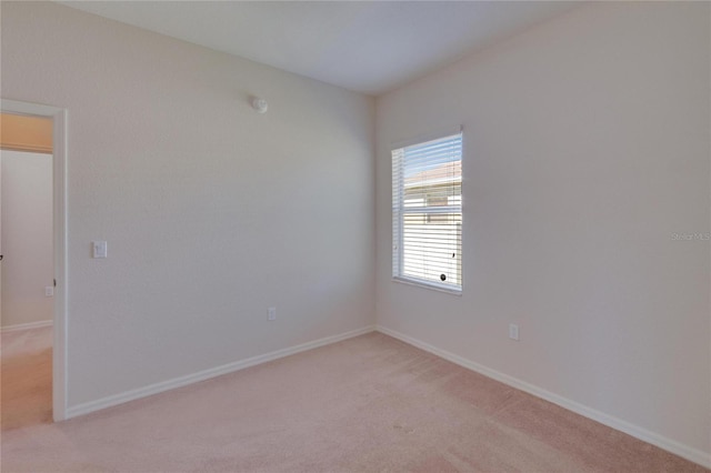 unfurnished room featuring light colored carpet and baseboards