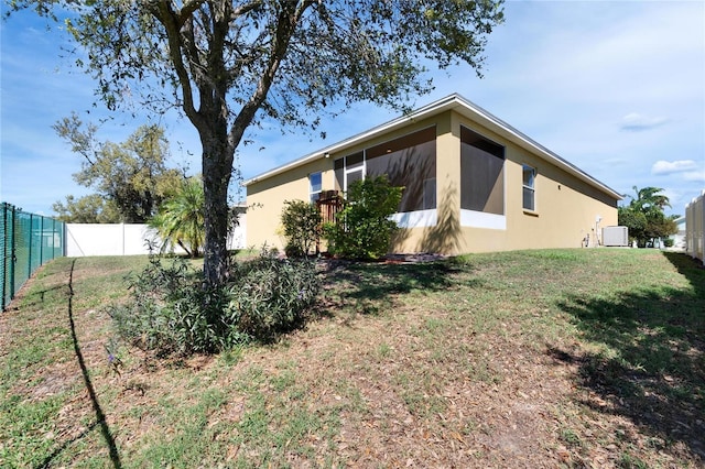 exterior space with a sunroom, a fenced backyard, a yard, and stucco siding