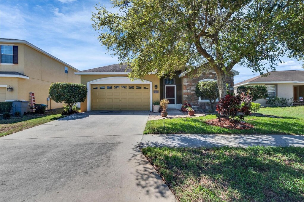 6432 Twin Bridges Dr, Zephyrhills, FL 33541 - view of front of property featuring stone siding, a garage, concrete driveway, a front yard, and stucco siding
