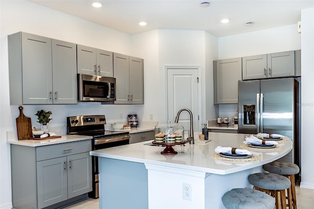 kitchen featuring gray cabinets, stainless steel appliances, and a kitchen breakfast bar