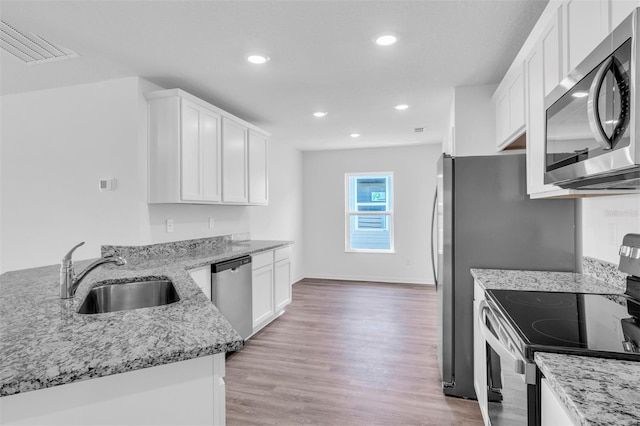 2674 SW 165th Street Rd, Ocala, FL 34473 - kitchen with appliances with stainless steel finishes, a sink, light wood-type flooring, light stone countertops, and recessed lighting