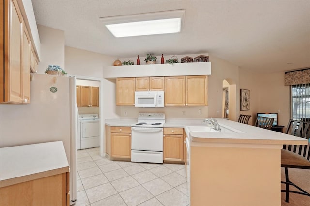 kitchen with a kitchen bar, white appliances, a peninsula, and light brown cabinets