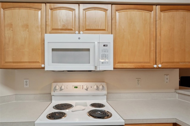 kitchen with white appliances, light brown cabinetry, and light countertops