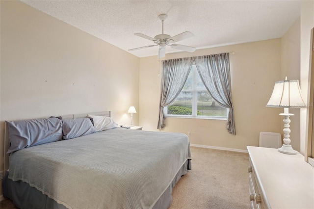 bedroom featuring a textured ceiling, a ceiling fan, baseboards, and light carpet