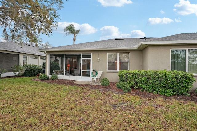 back of property with roof with shingles, a yard, a sunroom, and stucco siding