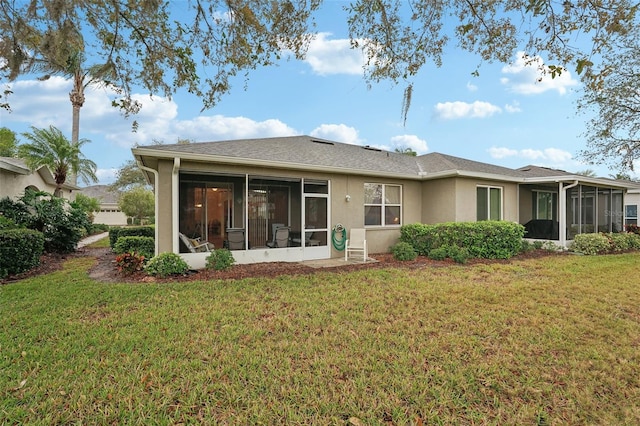 back of house with stucco siding, a yard, and a sunroom