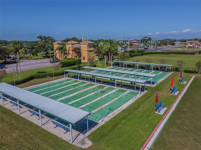 view of property's community featuring shuffleboard and a yard