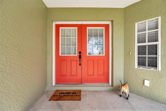 view of exterior entry with french doors, crawl space, and stucco siding