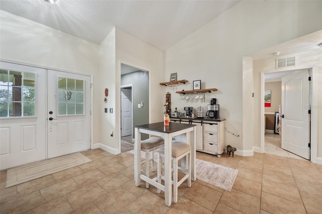 interior space featuring vaulted ceiling, french doors, visible vents, and baseboards