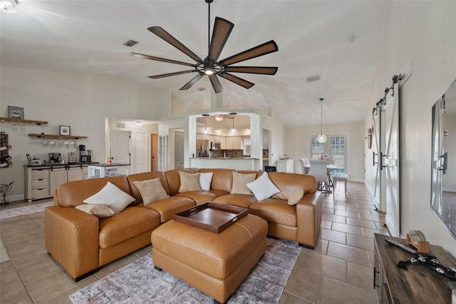 tiled living room with a ceiling fan, lofted ceiling, visible vents, and a barn door