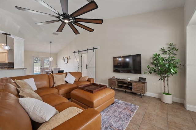 living area with a barn door, visible vents, baseboards, lofted ceiling, and light tile patterned flooring