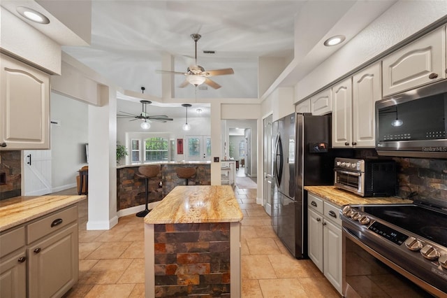 kitchen with light stone counters, a toaster, stainless steel appliances, decorative backsplash, and a center island