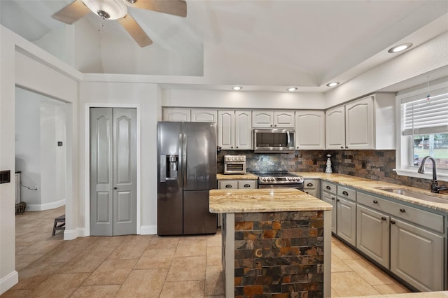 kitchen with decorative backsplash, appliances with stainless steel finishes, a center island, vaulted ceiling, and a sink