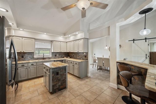 kitchen featuring a barn door, gray cabinetry, a sink, and freestanding refrigerator