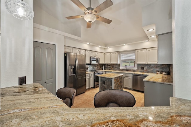 kitchen with a sink, appliances with stainless steel finishes, backsplash, and light stone countertops