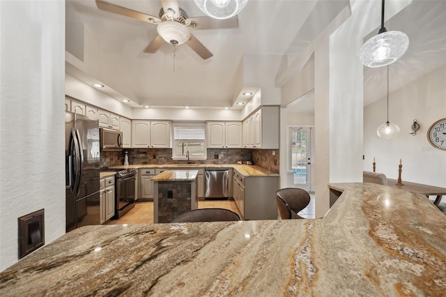 kitchen with a healthy amount of sunlight, light stone countertops, tasteful backsplash, and stainless steel appliances