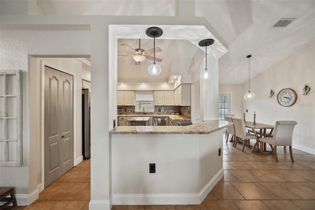 kitchen featuring tasteful backsplash, visible vents, lofted ceiling, light stone counters, and stainless steel dishwasher