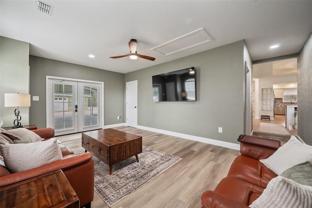 living area with baseboards, french doors, visible vents, and light wood-style floors