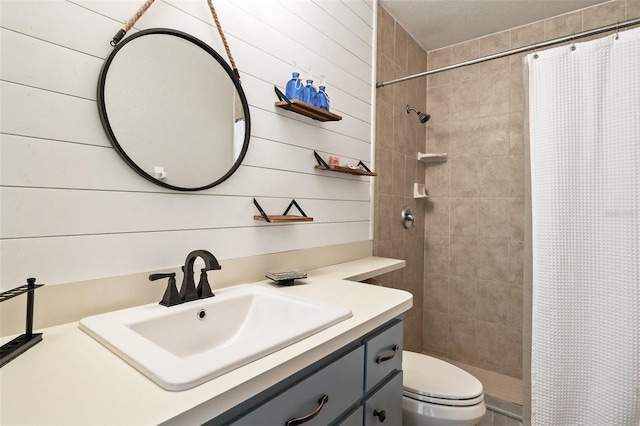 bathroom with toilet, wood walls, a stall shower, and vanity