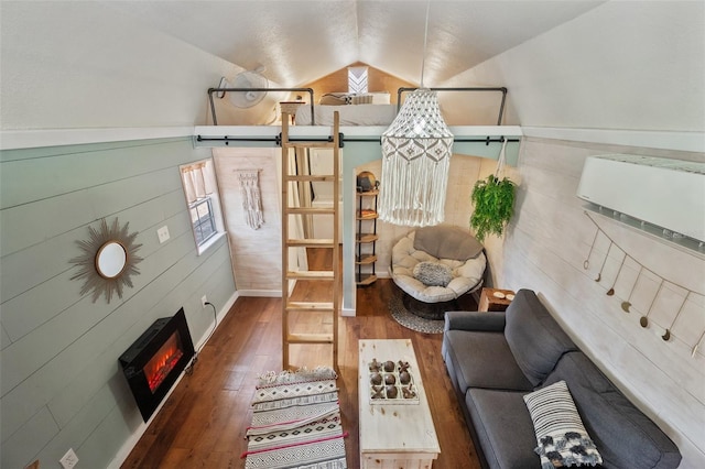 living area with hardwood / wood-style flooring, a warm lit fireplace, and vaulted ceiling