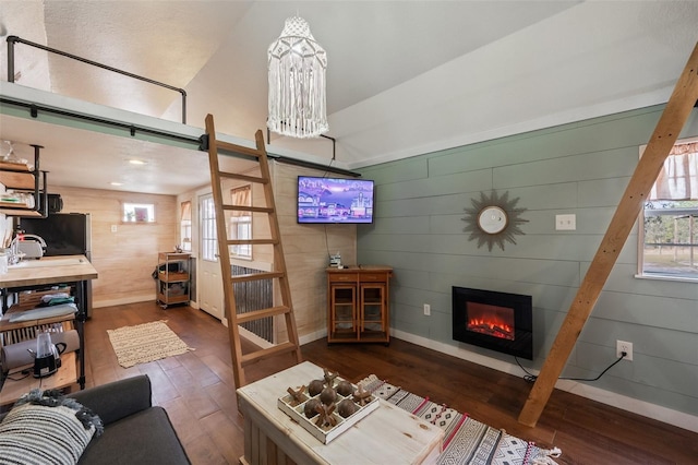 living area featuring a healthy amount of sunlight, a large fireplace, baseboards, and wood finished floors