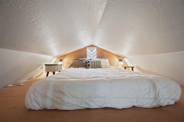 bedroom with vaulted ceiling, a textured wall, and a textured ceiling