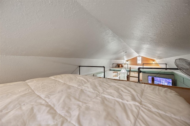 bedroom with lofted ceiling, a textured wall, and a textured ceiling