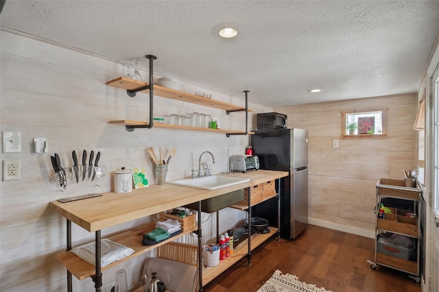 kitchen featuring black microwave, dark wood-style flooring, a sink, freestanding refrigerator, and open shelves